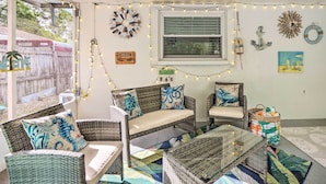 A cozy patio area with wicker furniture, string lights, and decorative wall hangings.