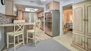 A modern kitchen with a central island, stainless steel appliances, and light wood cabinetry.