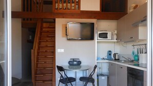 A compact kitchen with a microwave, coffee maker, and a small dining area with two chairs.