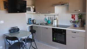 A compact kitchen with a dining area, including a microwave, coffee maker, and a dishwasher.