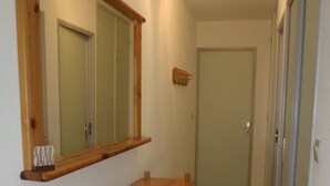 A narrow hallway with a wooden bench and a mirror on the wall. - APT 3 ROOMS 32m2 + TERRACE 13m2 REF 4050 (MARSEILLAN PLAGE)