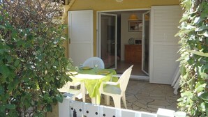 An outdoor patio area with a table and chairs, a white fence, and a door leading to an interior space. - APT 3 ROOMS 32m2 + TERRACE 13m2 REF 4050 (MARSEILLAN PLAGE)