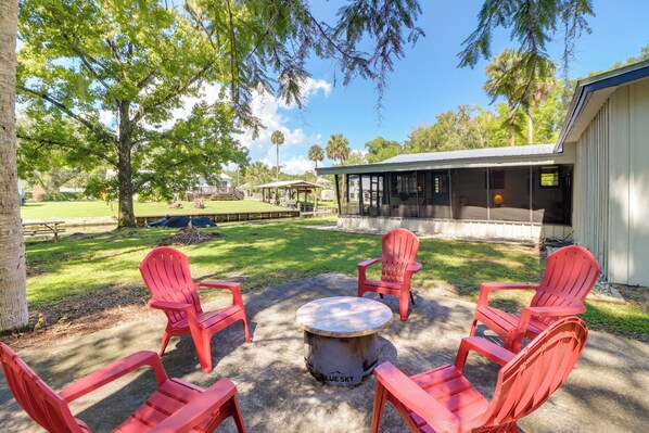 A patio with red Adirondack chairs and a round table labeled "BLUE SKY." - Charming Canalfront Retreat w/ Double Boat Slip! (Astor)