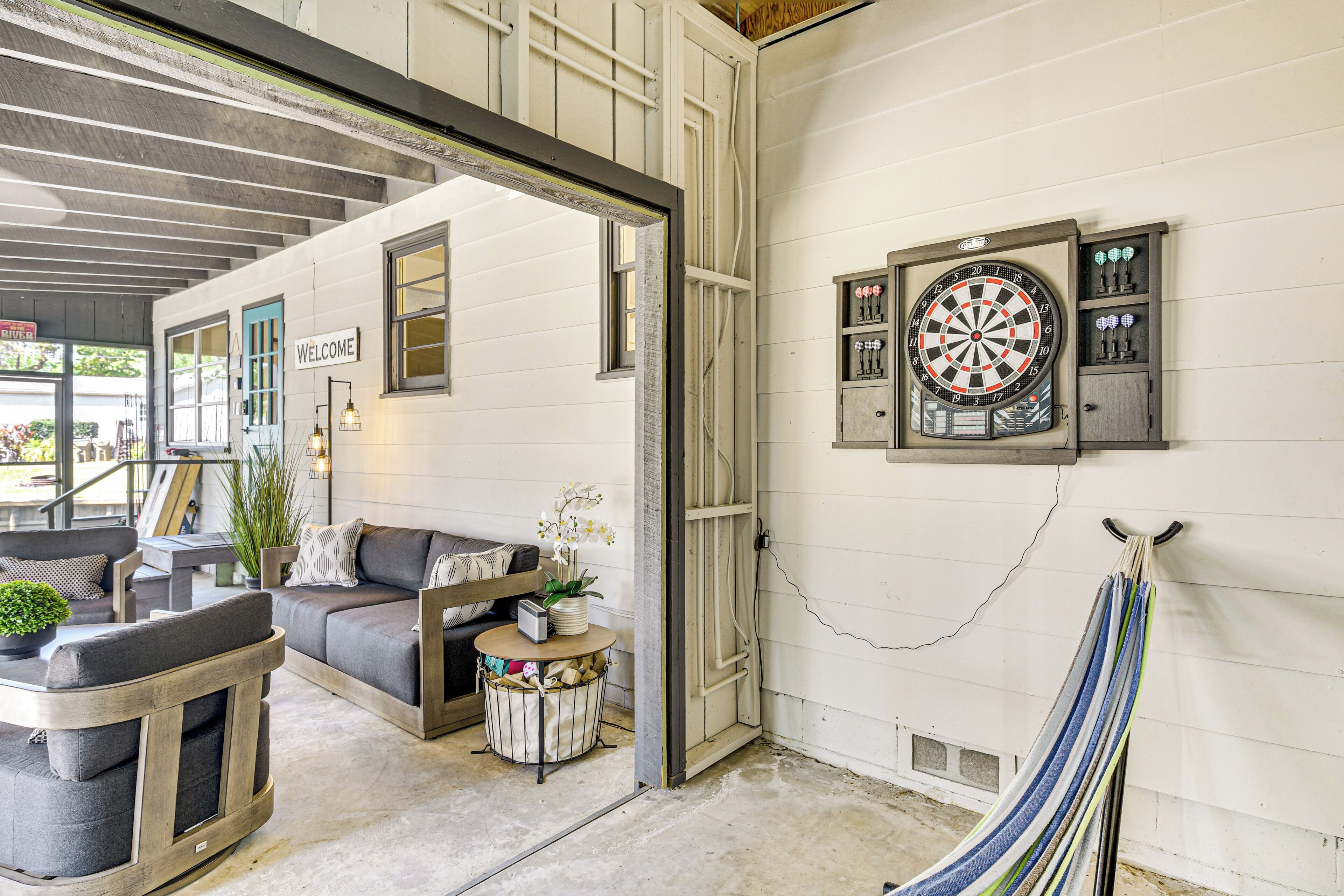 A room with a dartboard, a hammock, and a couch.