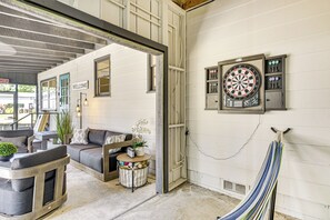 A room with a dartboard, a hammock, and a couch. - Charming Canalfront Retreat w/ Double Boat Slip! (Astor)