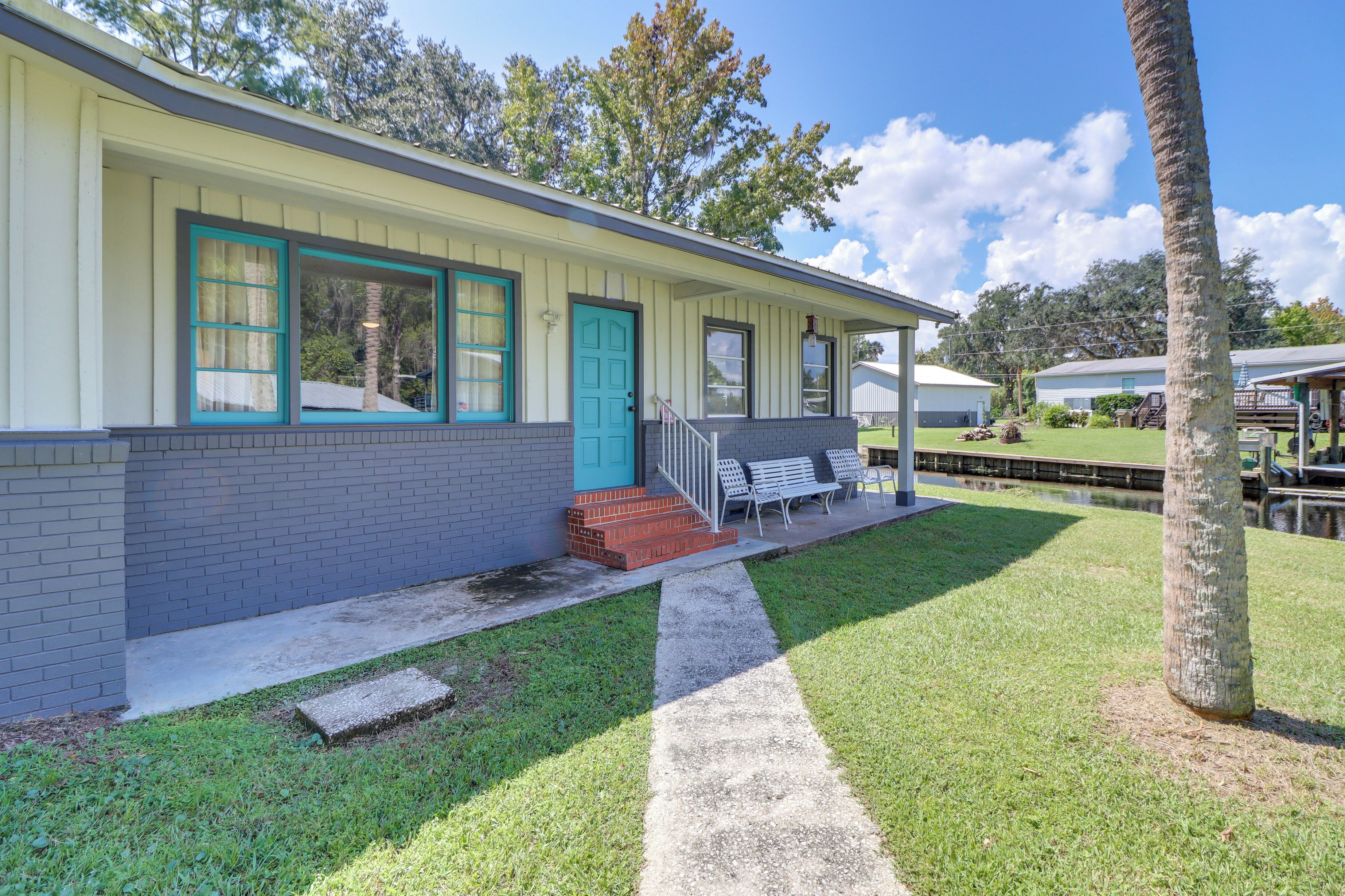 A single-story building with a porch, a blue door, and a small set of steps leading to the entrance.