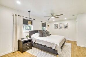 A bedroom with a bed, bedside tables, a ceiling fan, and a window with curtains. - Charming Canalfront Retreat w/ Double Boat Slip! (Astor)
