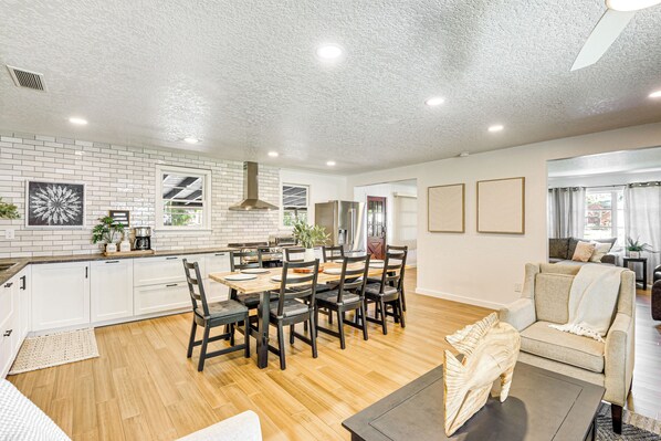 A spacious living area with a dining table, chairs, and a sofa.