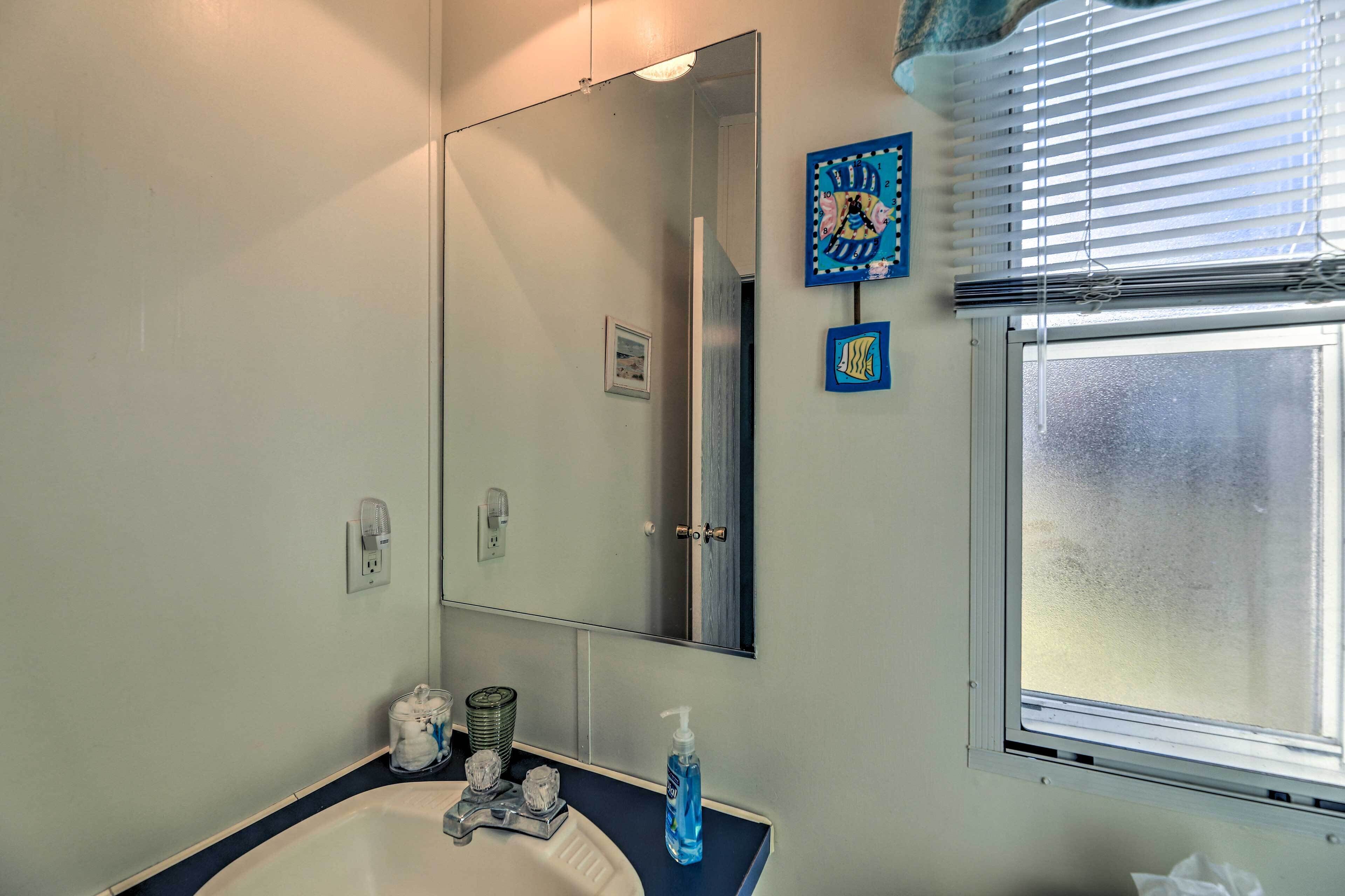 A bathroom with a sink, mirror, and window.