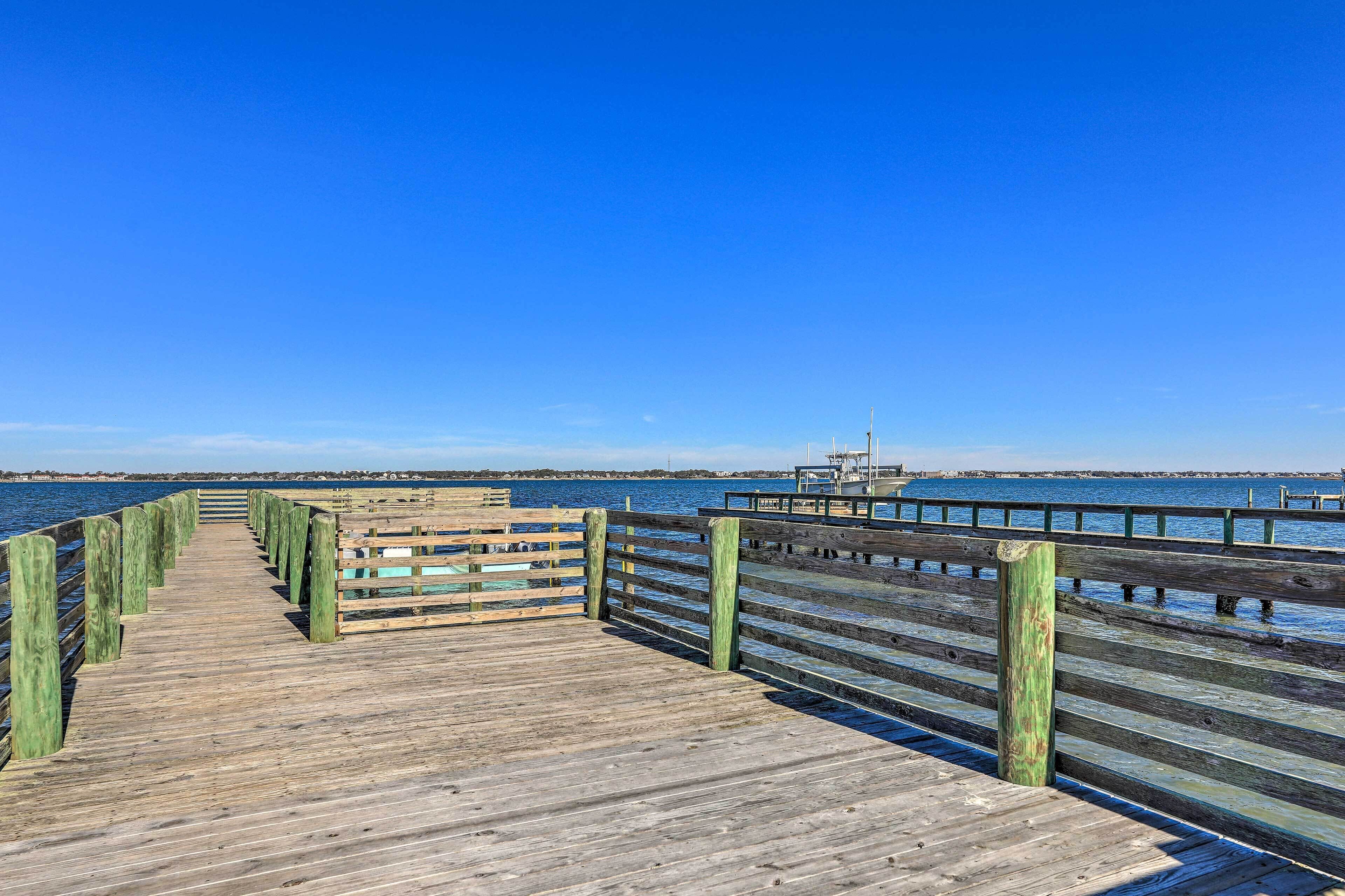 A wooden pier extending into a body of water with a clear blue sky above.