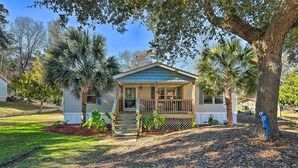 A single-story house with a front porch, surrounded by trees and a well-maintained lawn. - Atlantic Beach Home w/ Decks & Fire Pit (Atlantic Beach)