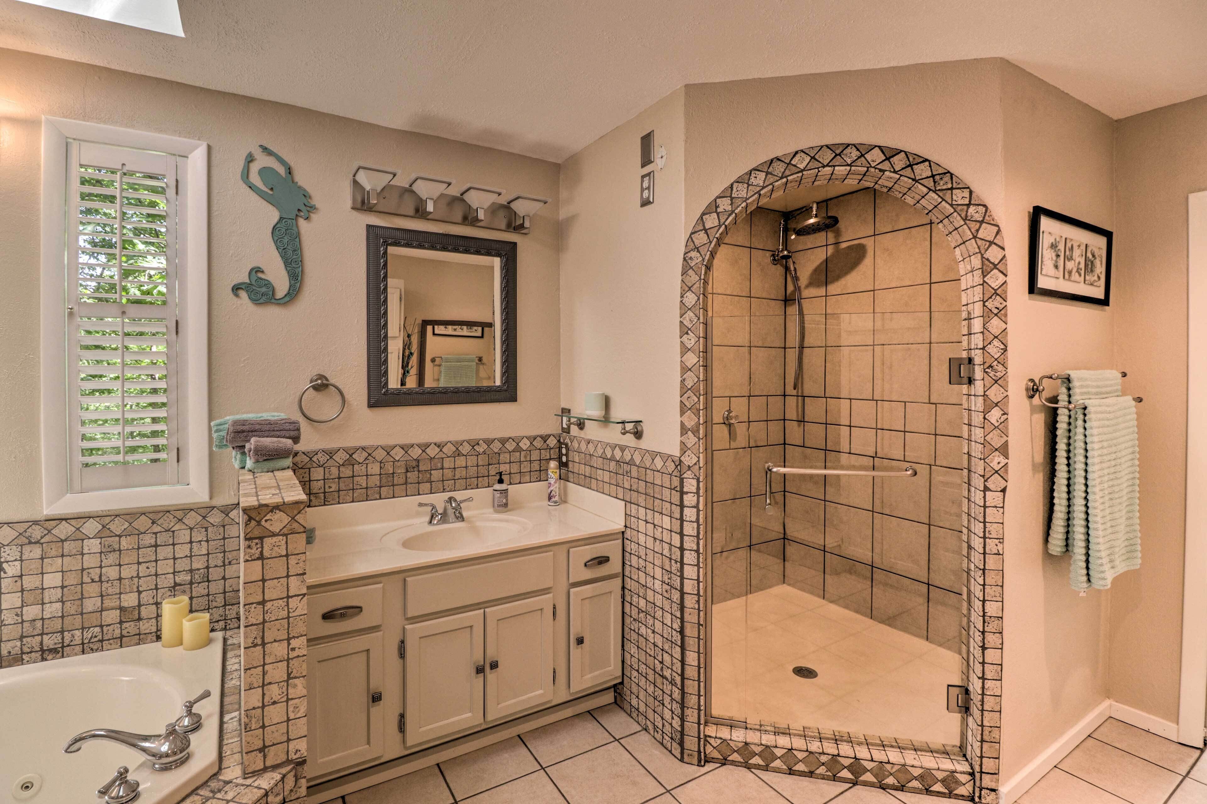 Une salle de bain dotée d’un meuble-lavabo à deux vasques, d’un grand miroir, d’une douche avec un espace clos carrelé et d’une décoration murale représentant un hippocampe.