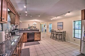 A spacious kitchen with a central island, wooden cabinets, and a dining area with chairs and a table.