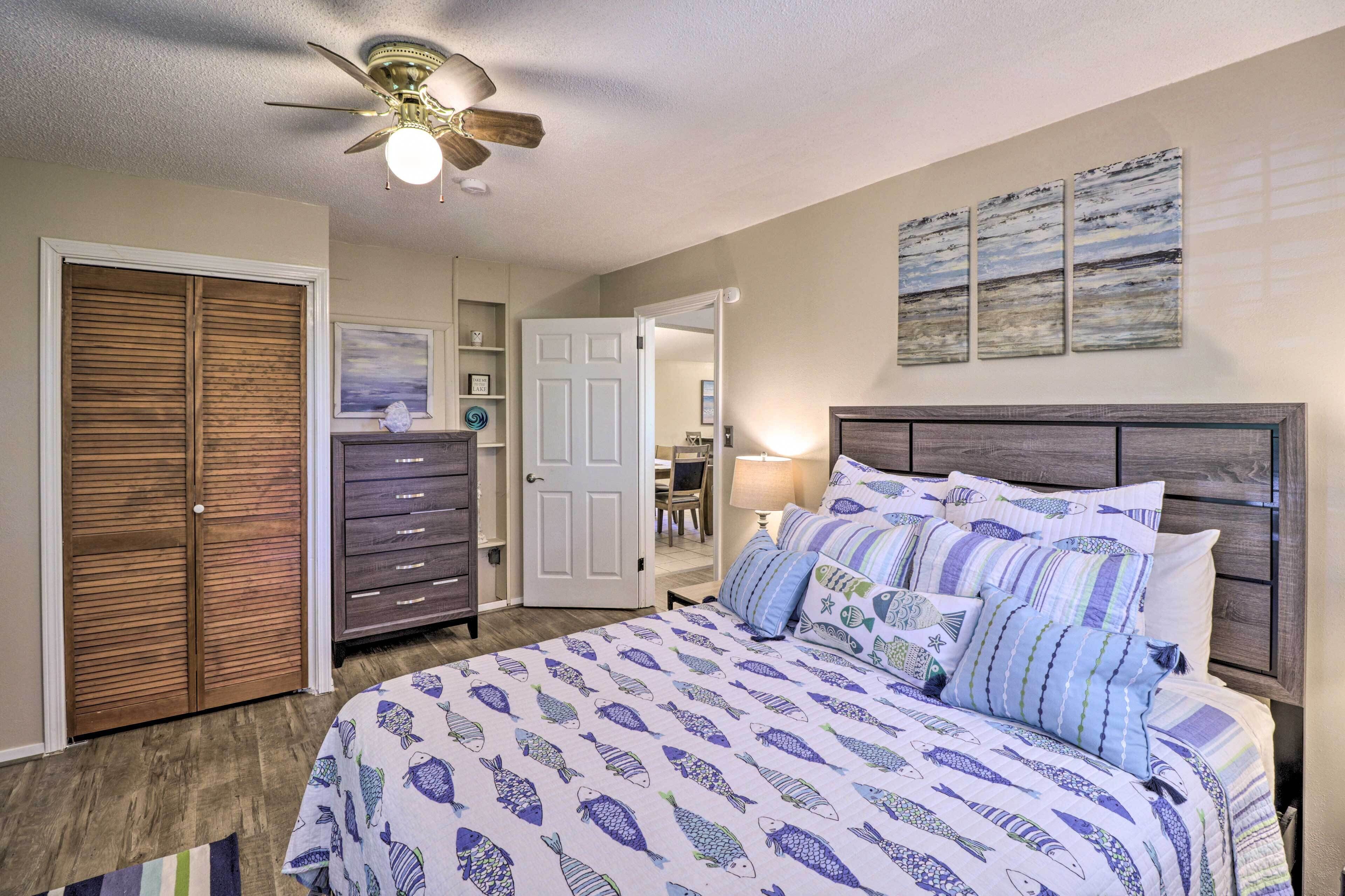 Une chambre à coucher comprenant un lit, un ventilateur de plafond, une armoire et une commode.