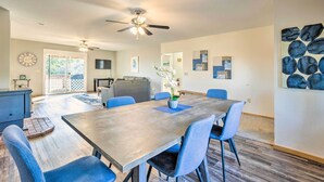 A spacious dining area with a large table, blue chairs, and a ceiling fan.