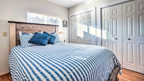 A bedroom with a bed, a wooden headboard, a window, and a set of white doors.