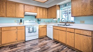 A modern kitchen with wooden cabinets, a white stove, and a dishwasher.