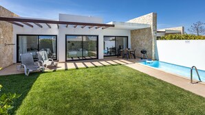 A modern house with a pool, covered patio, and a well-maintained lawn.