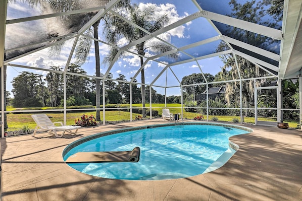 A covered swimming pool with a view of a lawn and trees.