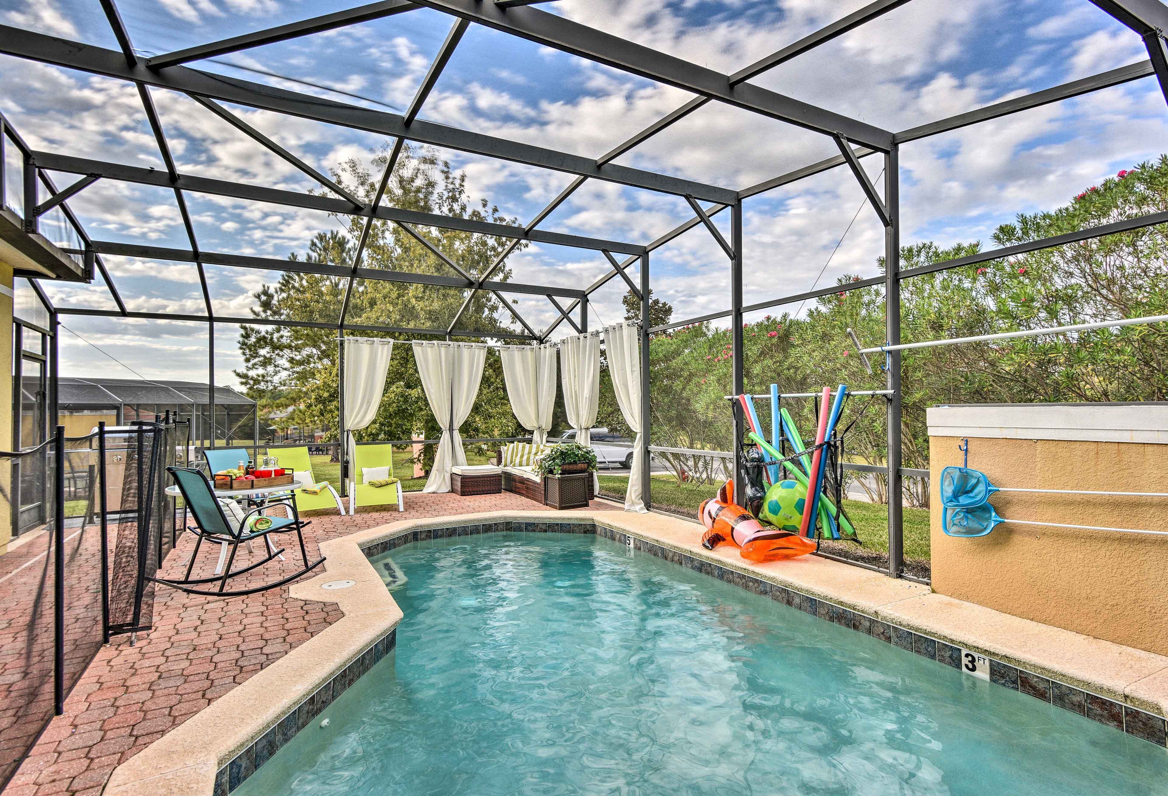 A covered outdoor swimming pool with a patio area, including a table and chairs, and a play structure.