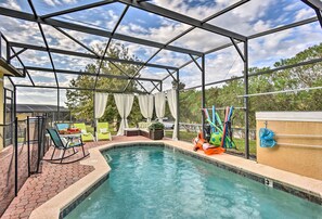 A covered outdoor swimming pool with a patio area, including a table and chairs, and a play structure.