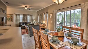 Un vaste espace de vie comprenant une table à manger pour quatre personnes, un canapé et un ventilateur de plafond.