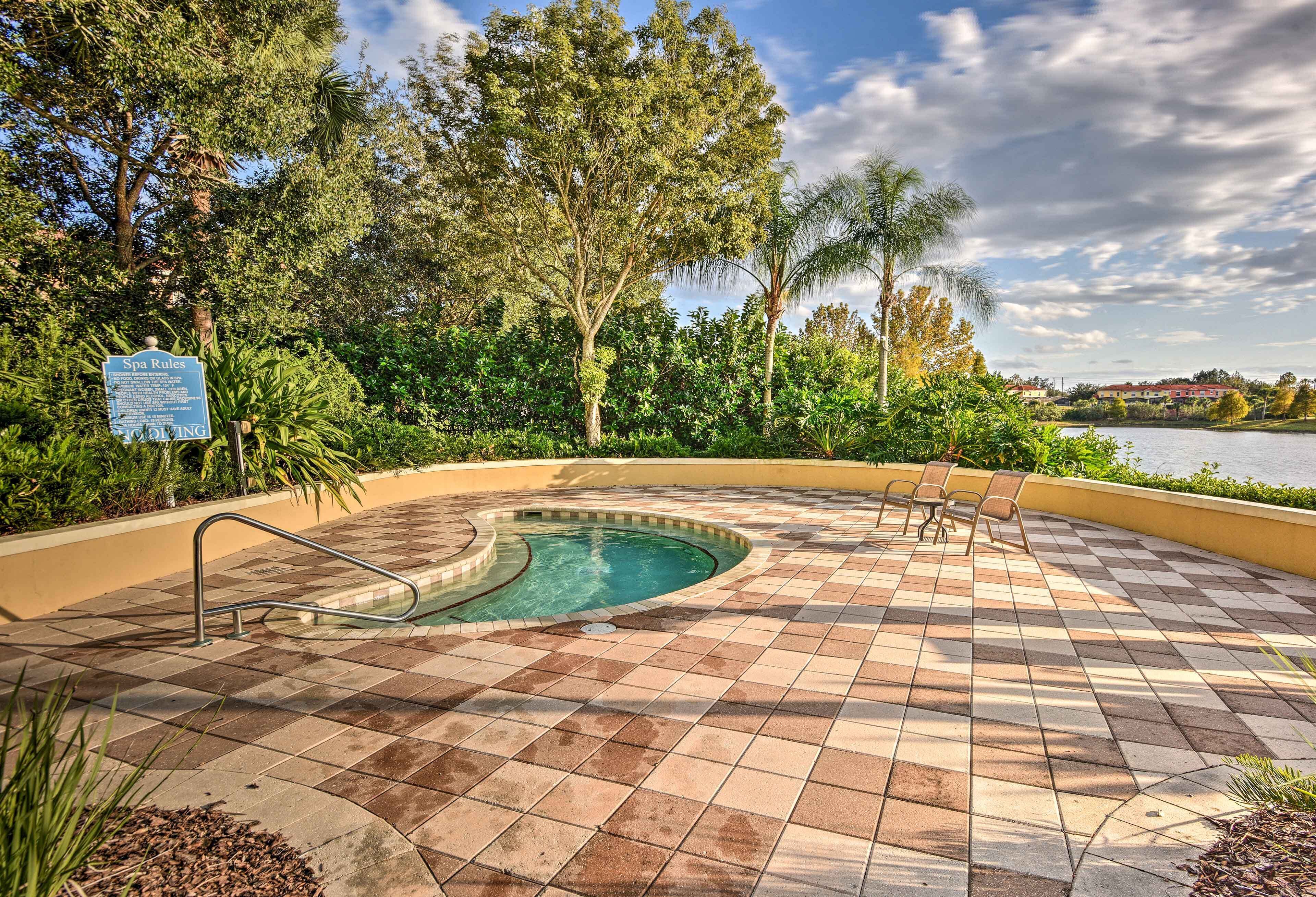 A spa pool area with a tiled deck, a sign indicating spa rules, and surrounding greenery.