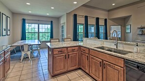 A modern kitchen with granite countertops, wooden cabinets, and a built-in dishwasher. - Expansive Townhome w/ Game Room & Community Pool (Branson West)