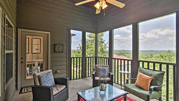 A covered porch with wicker furniture, a glass table, and a view of the landscape. - Expansive Townhome w/ Game Room & Community Pool (Branson West)