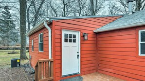 A red wooden house with a white door, a small porch, and a black heater on the ground. - Indiana Vacation Rental Near Lake Michigan (Valparaiso)