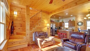 A wooden cabin interior with a staircase, leather sofas, a dining area, and a kitchen. - Decks, Panoramic Views! Mtn Retreat in Sparta (Sparta)