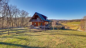 A wooden cabin with a porch, surrounded by a fenced yard and trees. - Decks, Panoramic Views! Mtn Retreat in Sparta (Sparta)