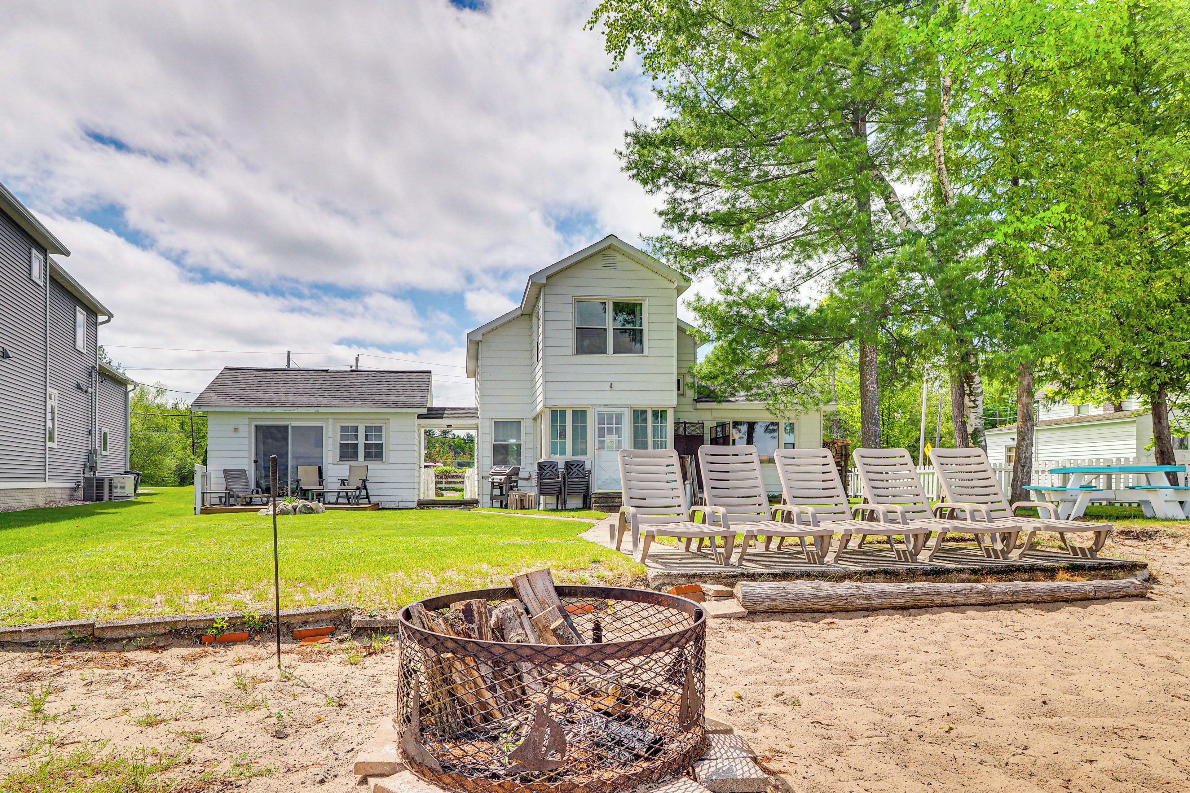 A residential area with two houses, a grassy yard, and outdoor seating.
