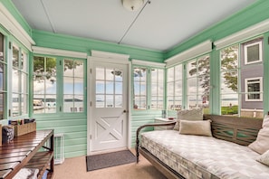 A room with a bed, a bench, and a table with a basket.