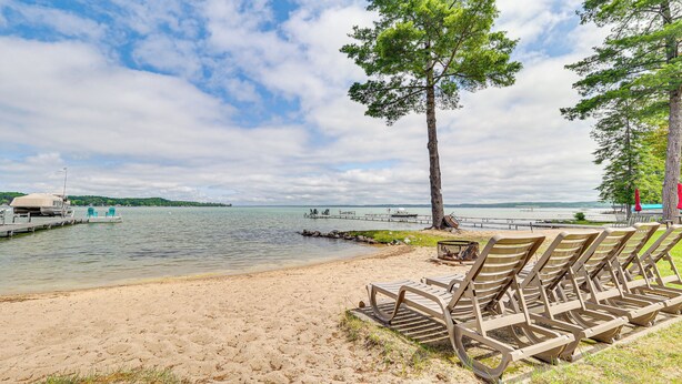 Ein Strand mit Liegestühlen, einem Steg und freiem Blick auf das Wasser.