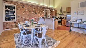 A modern kitchen with a brick backsplash, wooden cabinets, and a dining area with white chairs and a patterned rug. - Pet-friendly Cottage With Game Room & Fire Pit! (Reva)