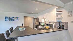 A modern kitchen with a central island, white cabinetry, and a granite countertop.