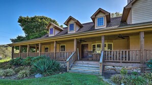 A two-story house with a covered porch, a front door, and a small patio area. - Game Room, Theater + Deck: Burnsville Cabin! (Burnsville)