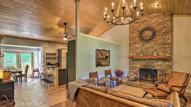 A cozy living room with a stone fireplace, wooden ceiling, and a comfortable sofa. - Game Room, Theater + Deck: Burnsville Cabin! (Burnsville)