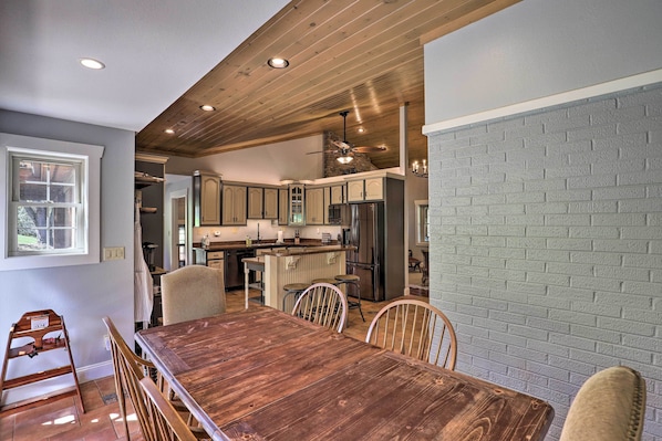 A spacious kitchen with wooden cabinets, a central island, and a dining area with a wooden table and chairs.