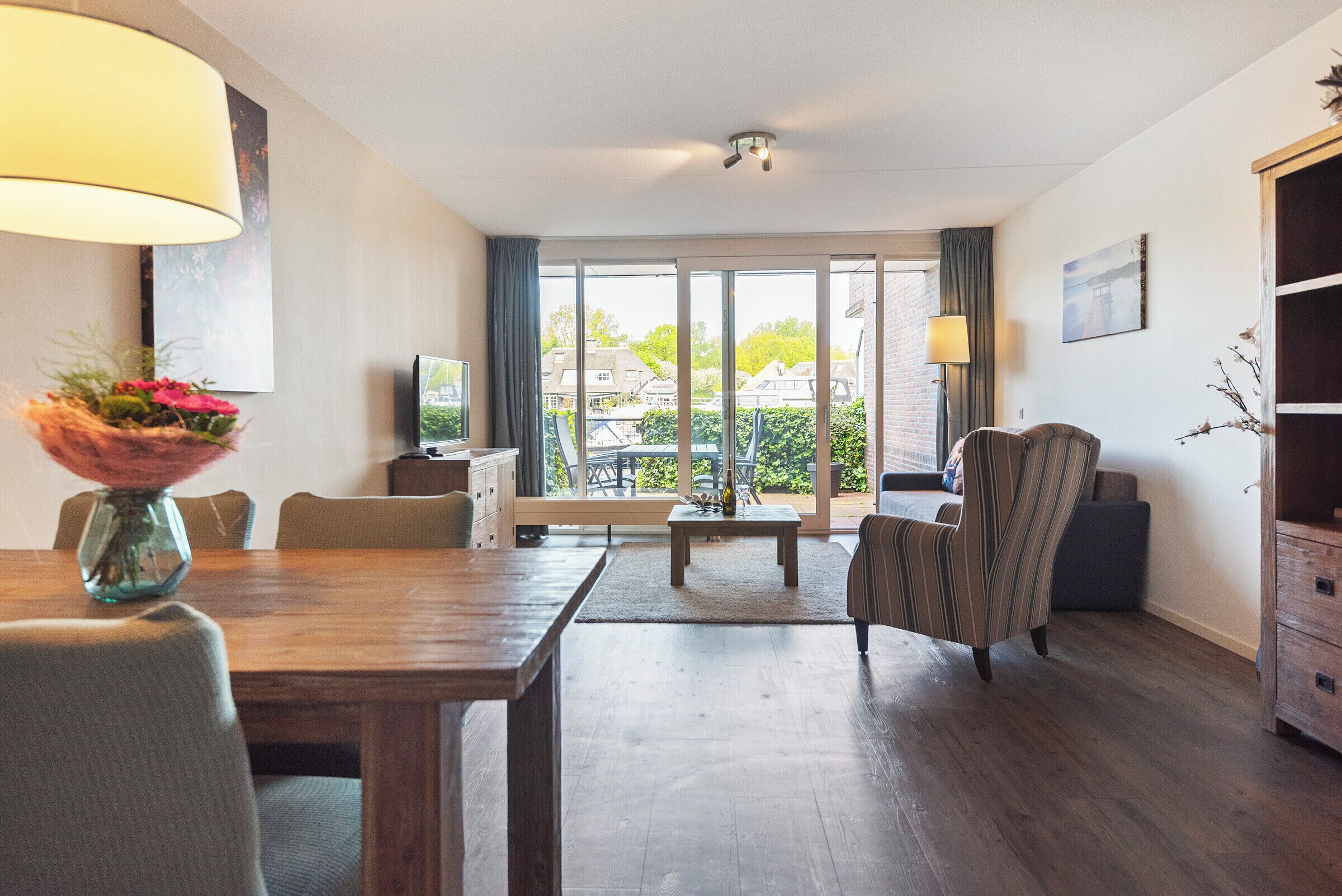 Una sala moderna con una mesa de comedor de madera, un sofá y un televisor.