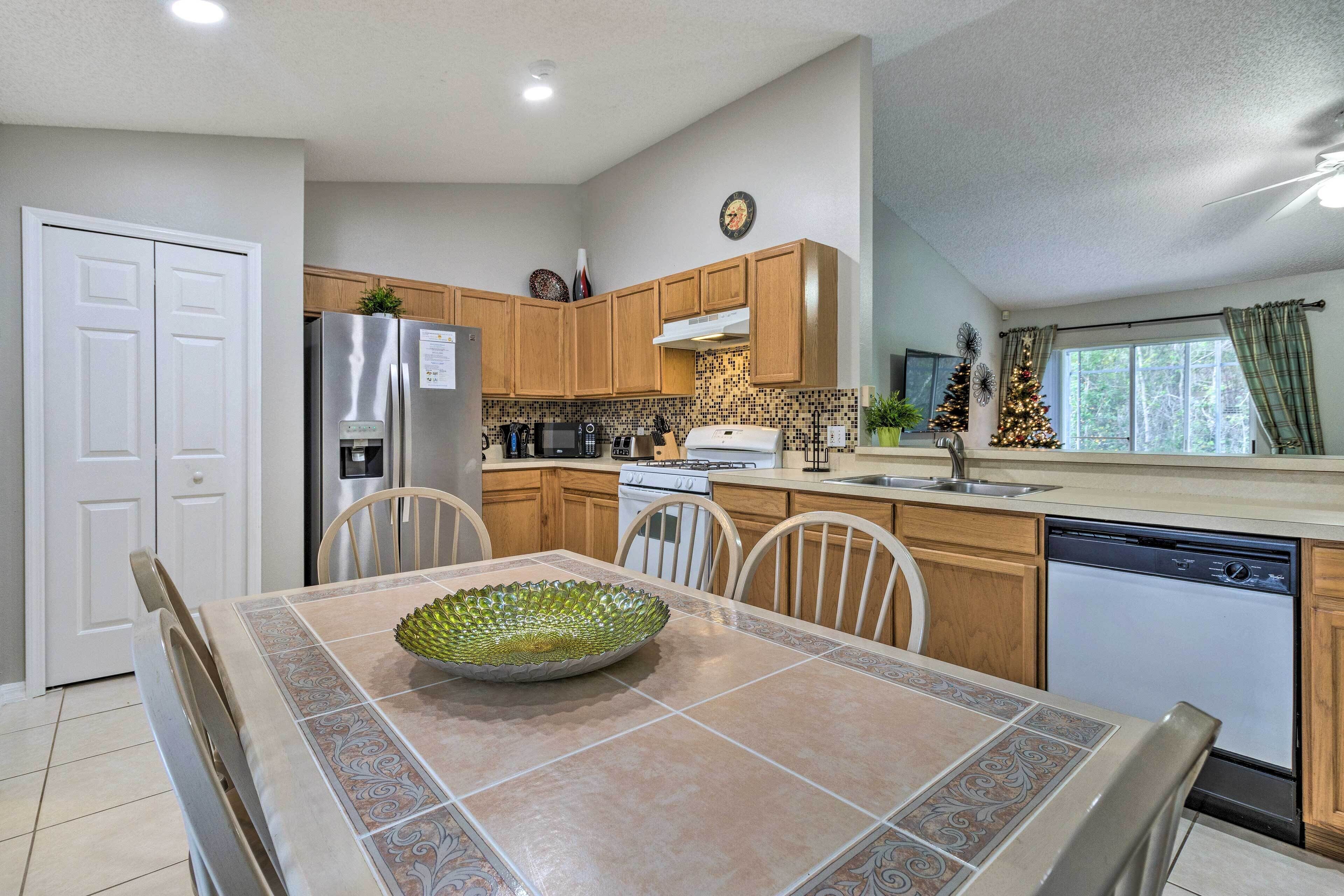 A modern kitchen with wooden cabinets, a stainless steel refrigerator, a dishwasher, and a dining table with chairs.