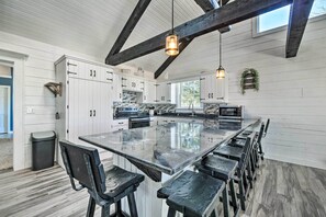 A spacious kitchen with a large island, wooden beams, and white cabinetry. - Spacious Massillon Log Cabin w/ Fire Pit! (Massillon)