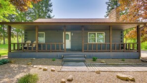 Une cabane en rondins avec une véranda, deux fenêtres et une porte.