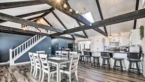 Une cuisine spacieuse avec de hauts plafonds, des poutres apparentes et un îlot central.