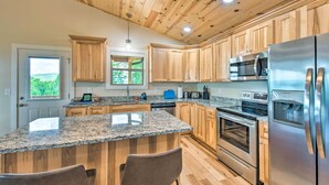 A modern kitchen with granite countertops, wooden cabinets, stainless steel appliances, and a large island with bar stools. - 'mountain Sky Escape' Murphy Cabin w/ Mtn Views (Murphy)
