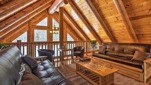 A cozy, wooden-floored living room with a leather sofa, a coffee table, and a fireplace.