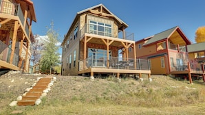 A multi-story wooden building with balconies, a covered porch, and a staircase leading up to the entrance.