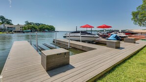 A wooden dock with a boat docked, red umbrellas, and a grassy area. - Lakefront Montgomery Home w/ Porch & Dock! (Montgomery)
