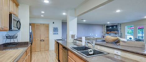A kitchen with wooden cabinets, a granite countertop, a built-in oven, and a large window.